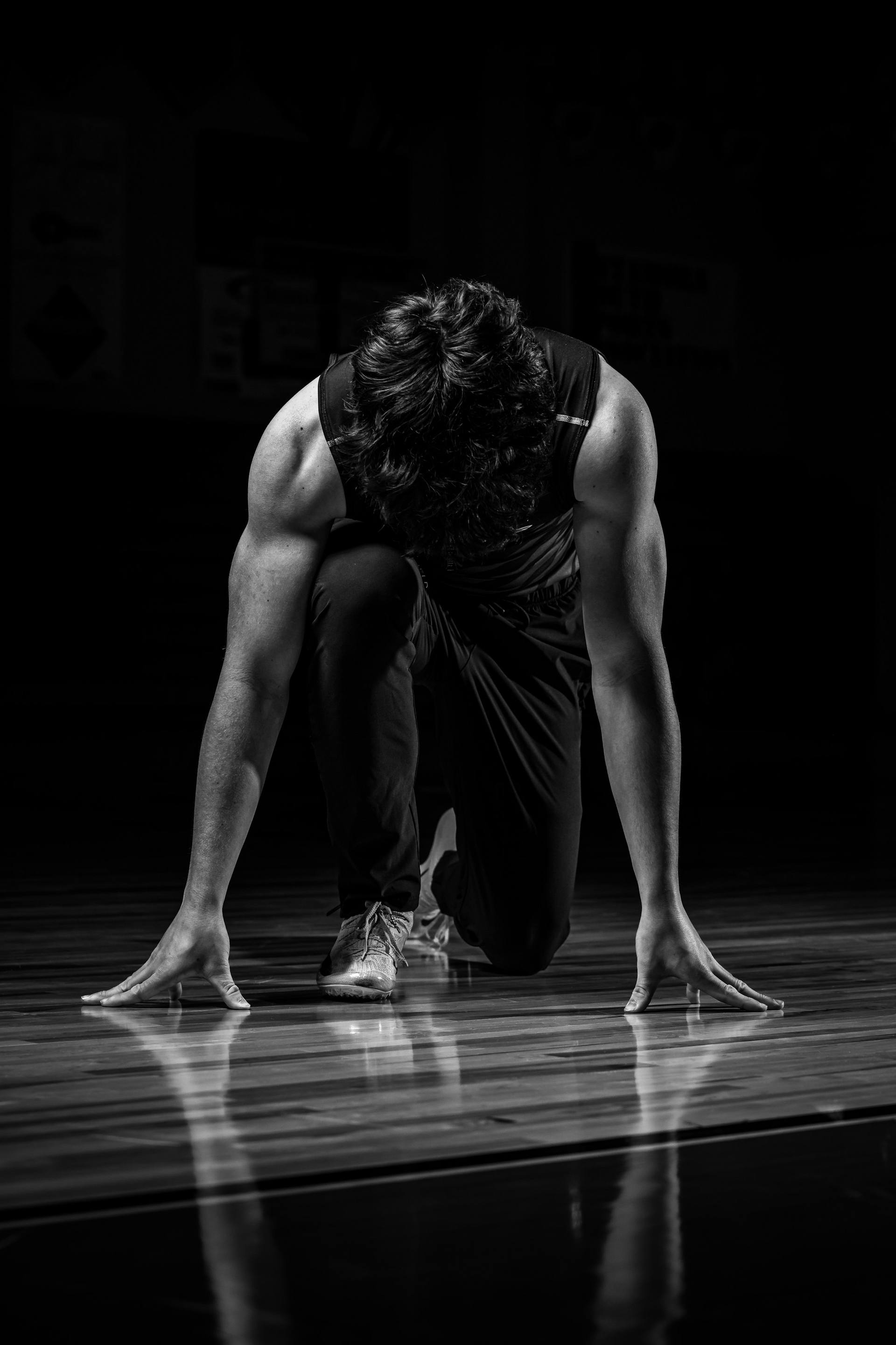 Atleta en posición de salida sobre la pista, en blanco y negro